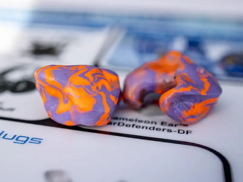 closeup of orange and purple hearing protection molds on desk mat